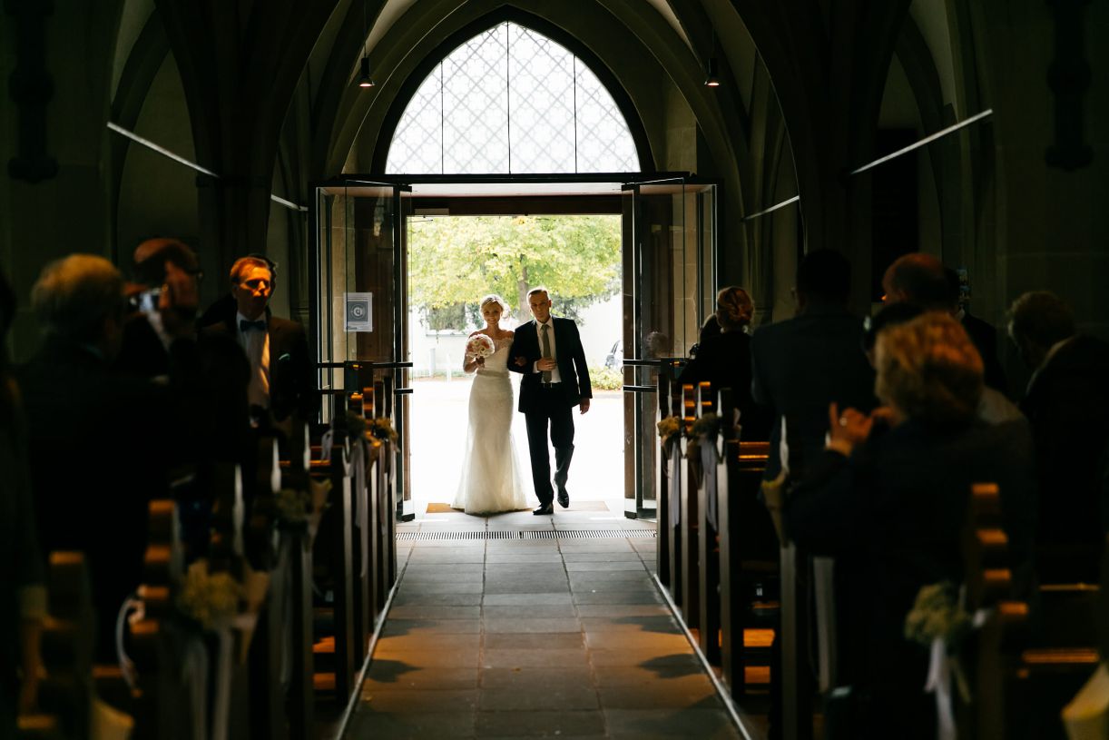 Kirchliche Trauung. Der Brautvater führt die Braut zum Altar. Hochzeitsfotograf in Schweinfurt.