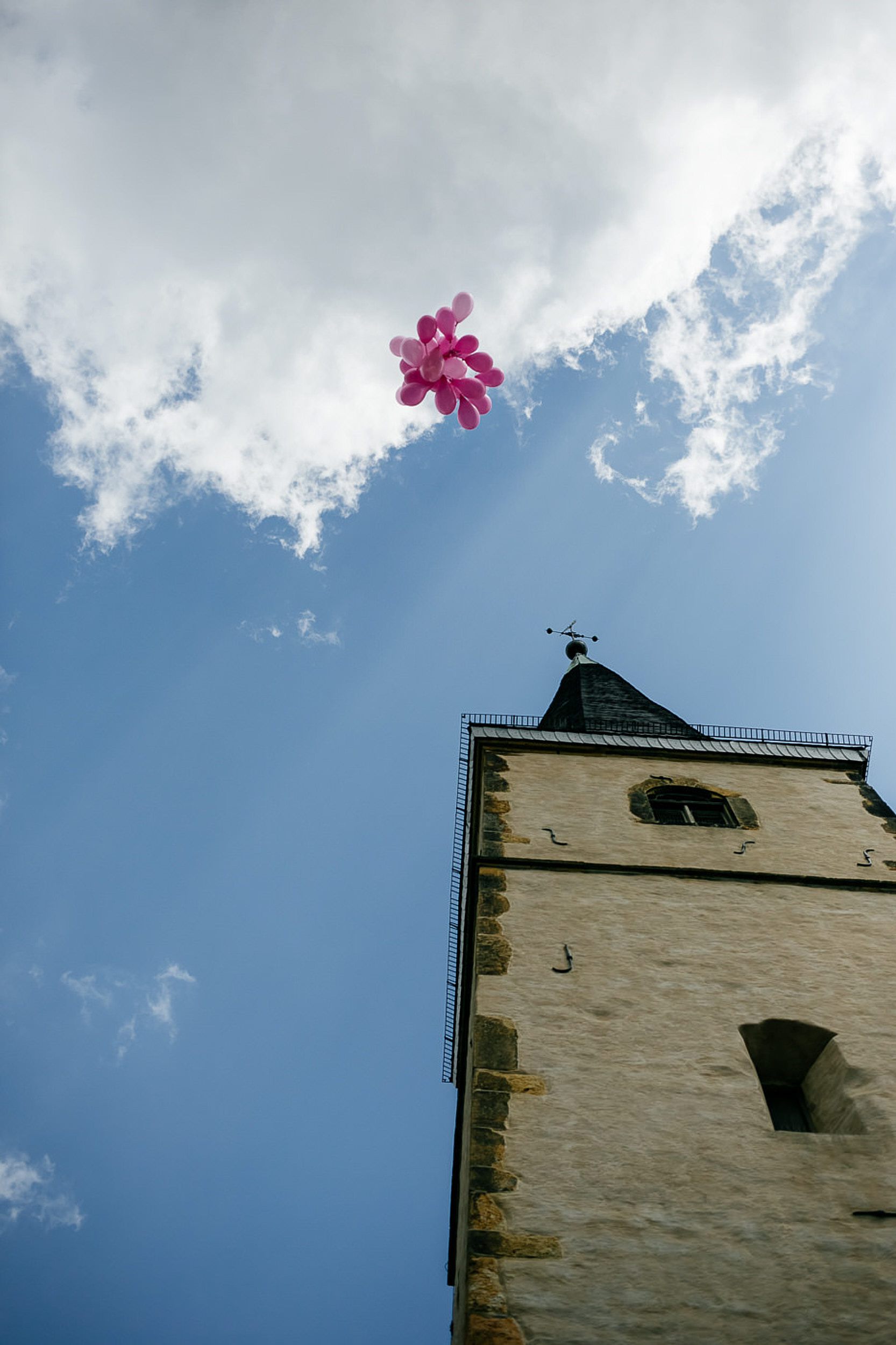 Kirchliche Trauung. Pinke Luftballons in der Luft neben dem Kirchenturm..