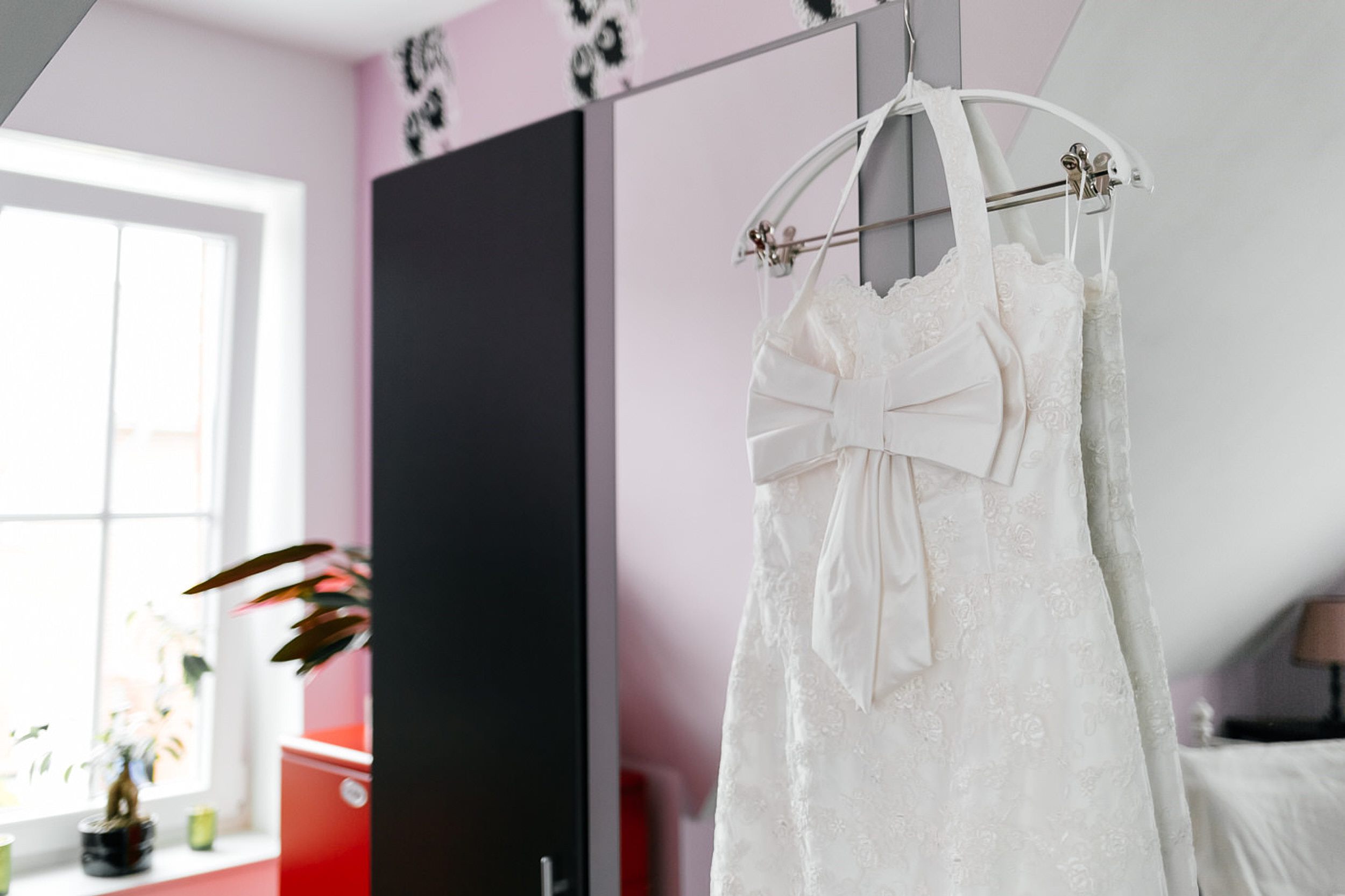 Brautkleid hängt an dem Schrank.