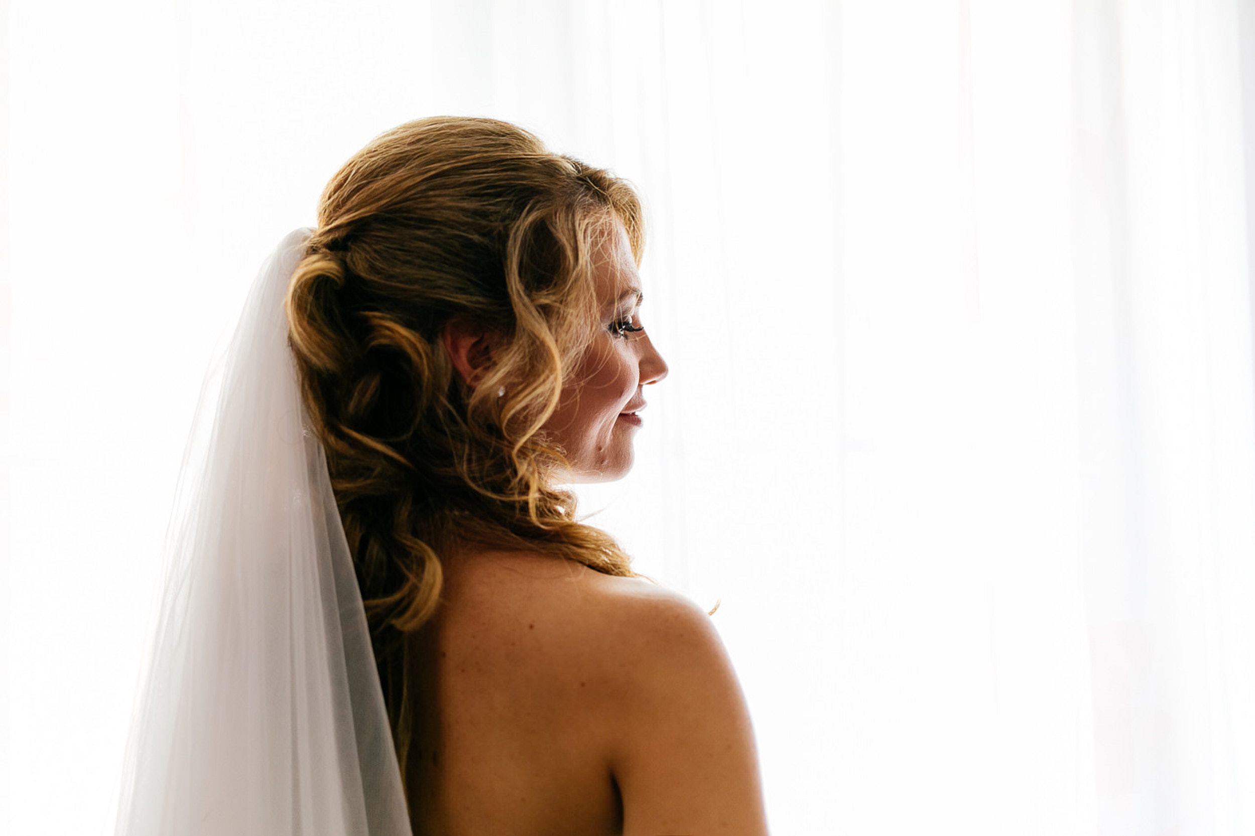 Braut steht vom Fenster. Portrait im Profil.