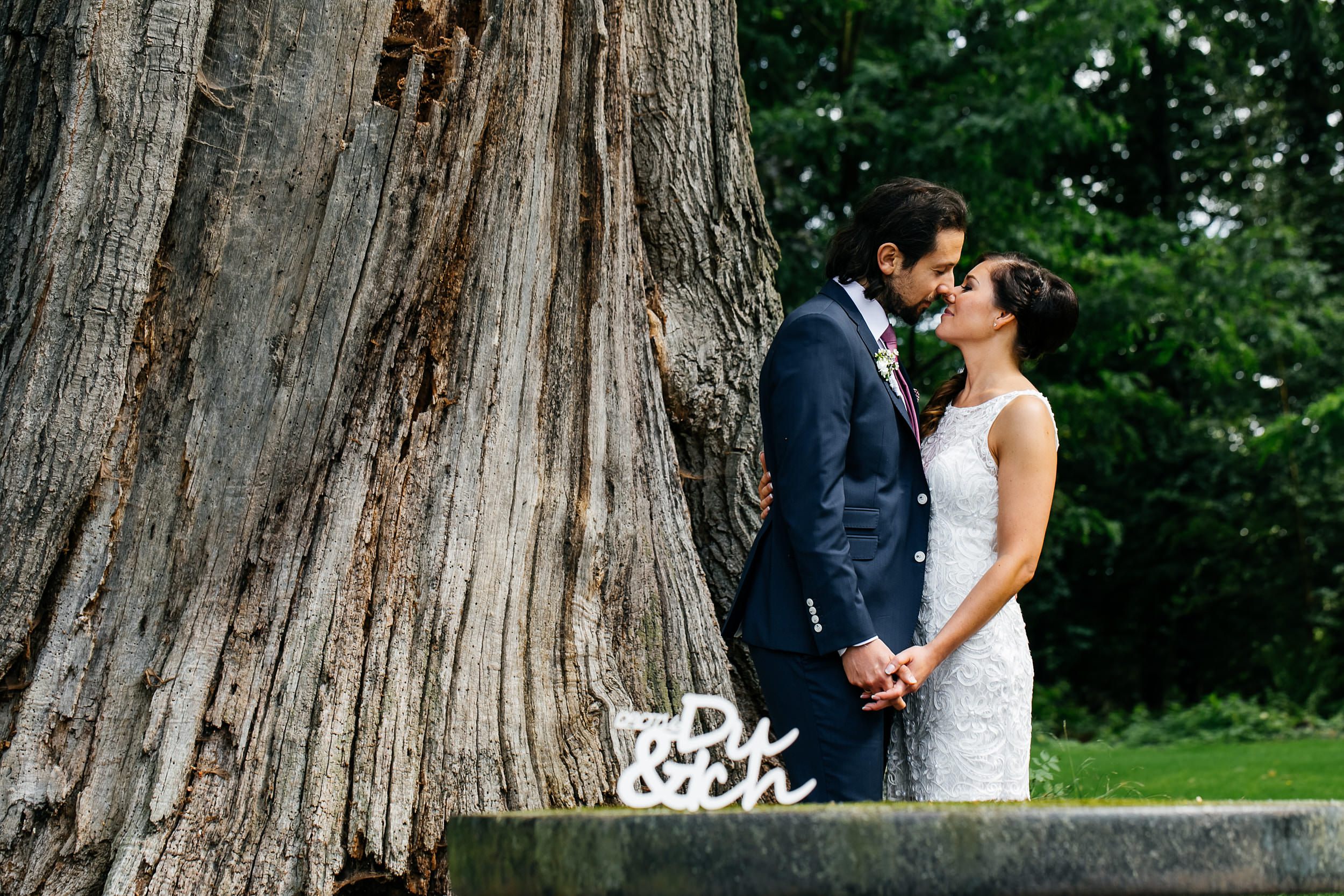Standesamtliche Trauung auf Gut Eckendorf. Das Brautpaar beim Fotoshooting neben einem großen Baum. Hochzeitsfotograf in Bielefeld.