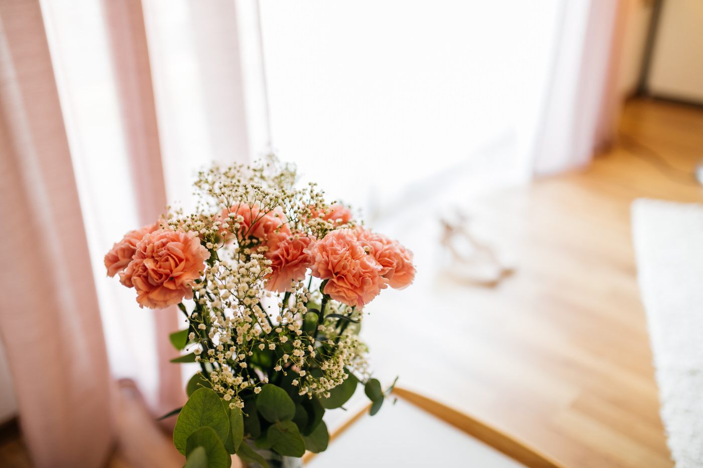 Vorbereitungen der Braut. Blumenstrauß neben einem mit lichterfülltem Fenster. Als Hochzeitsfotograf in Bad Ems.