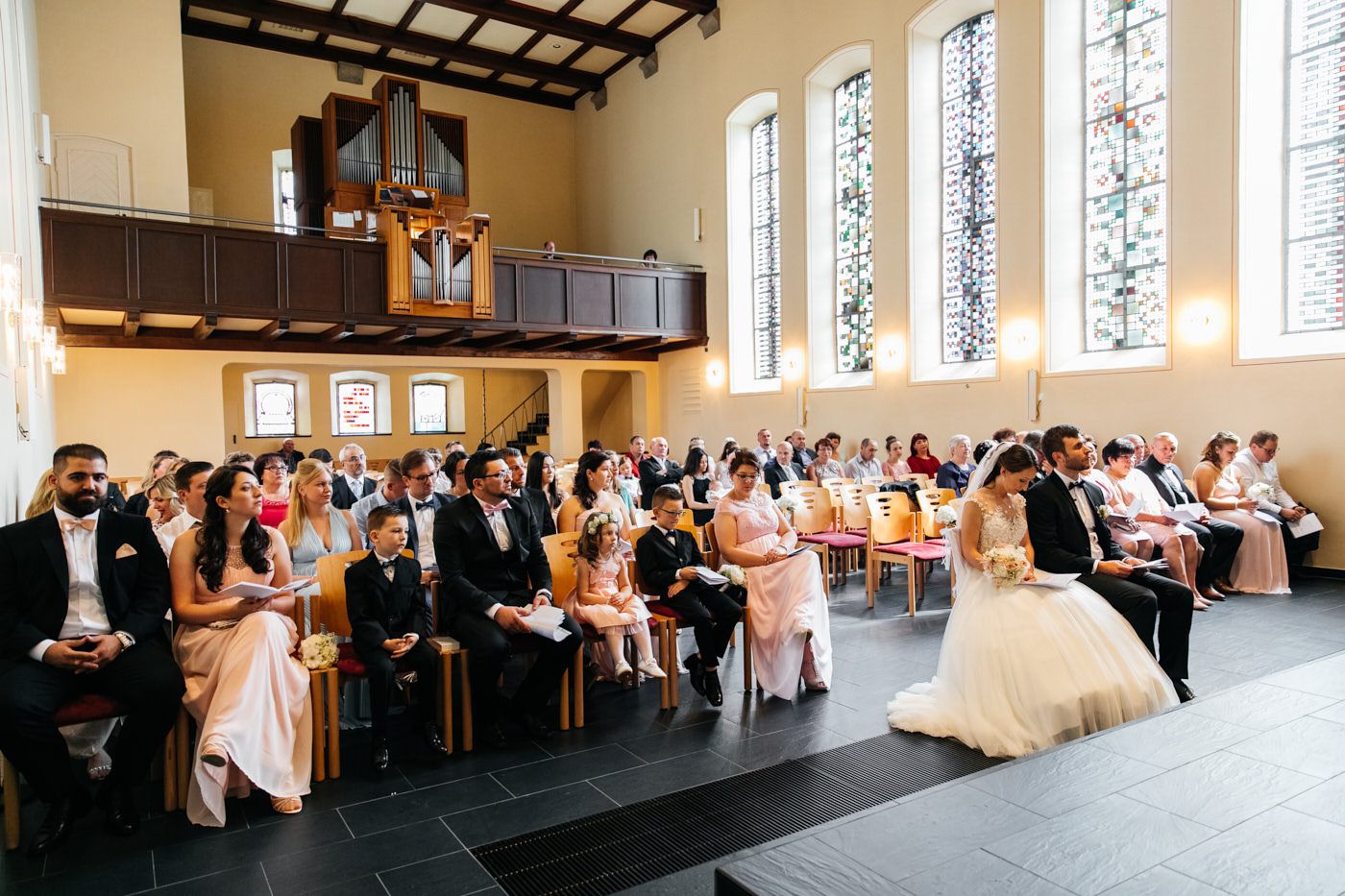 Alle sitzen in der Kirche im Vordergrund ist das Brautpaar. Hochzeitsfotograf in Bad Ems.