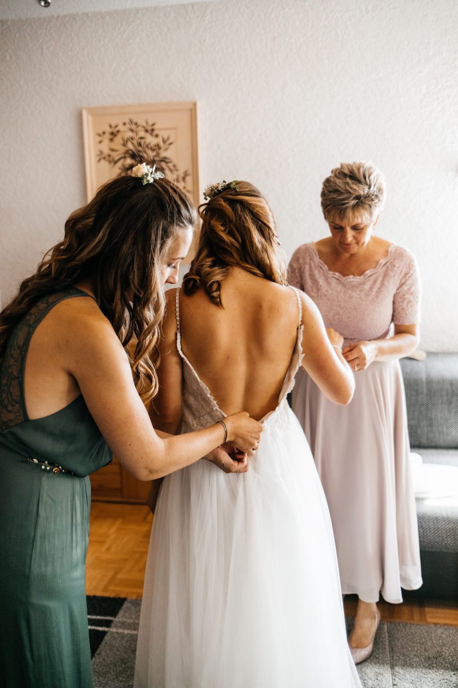 Hochzeitsfotograf hält den Moment fest, als die Braut angezogen wird.