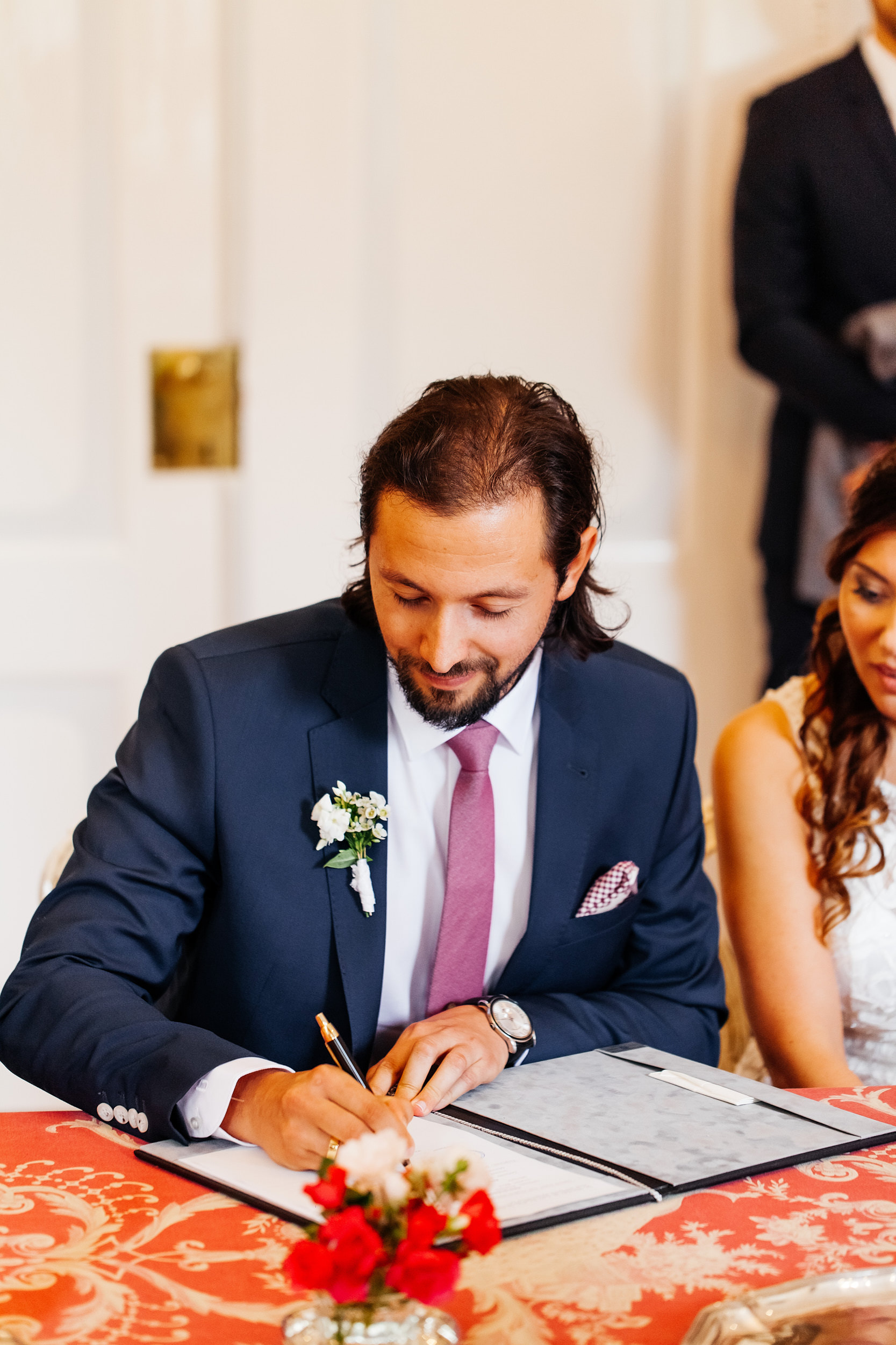 Standesamtliche Trauung auf Gut Eckendorf. Der Bräutigam unterschreibt die Heiratsurkunde. Hochzeitsfotograf in Bielefeld.