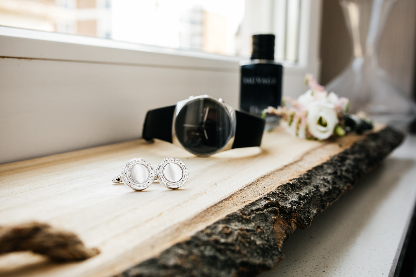 Uhr, Manschettenkn&ouml;pfe, Parfum und Blumen liegen auf einer Holzunterlage. Als Hochzeitsfotograf in Bad Ems.