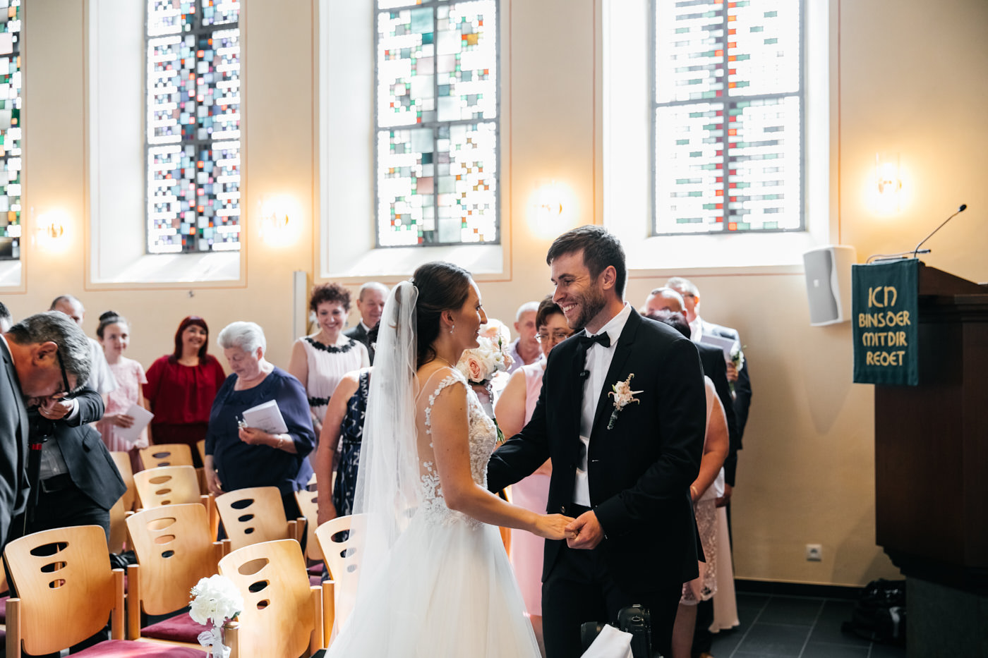 Braut und Br&auml;utigam in der Kirche H&auml;ndchen haltend. Hochzeitsfotograf in Bad Ems.