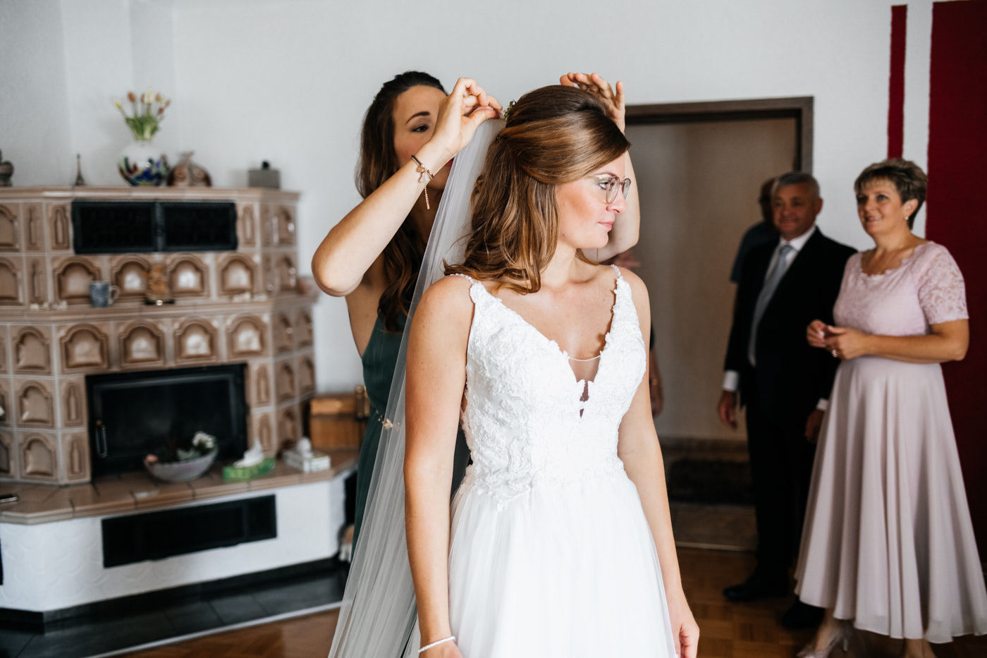 Hochzeitstag, die Vorbereitung der Braut. Die Trauzeugin bringt der Braut den Brautschleier an.