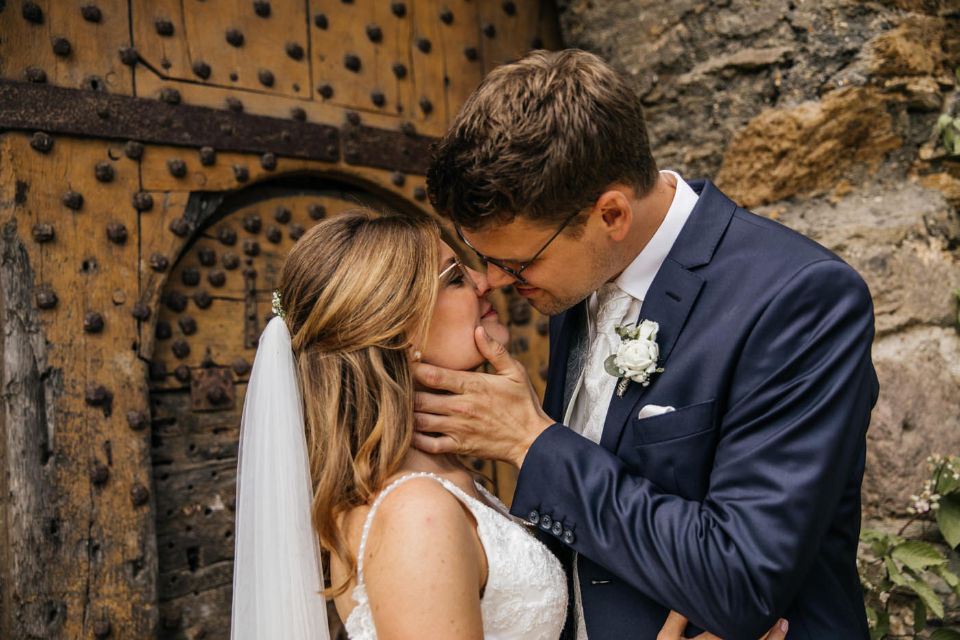 Fotoshooting am Hochzeitstag. Brautpaar k&uuml;sst sich vor der Burgmauer Hochzeitsfotograf f&uuml;r Koblenz.