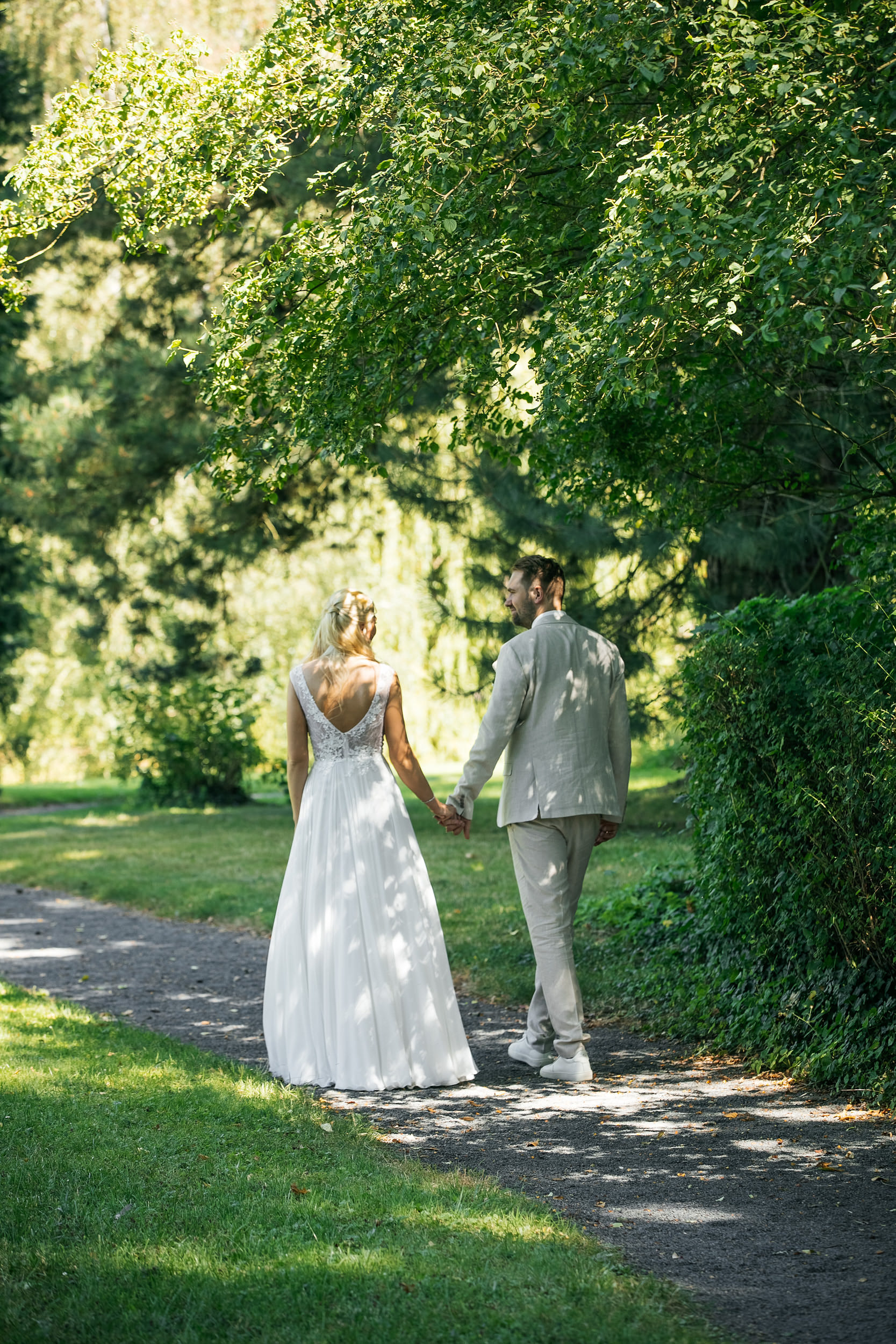 Standesamtliche Trauung in Gut Eckendorf. Brautpaar-Fotoshooting, das Brautpaar spaziert auf einem Weg im Park. Hochzeitsfotograf in Bielefeld
