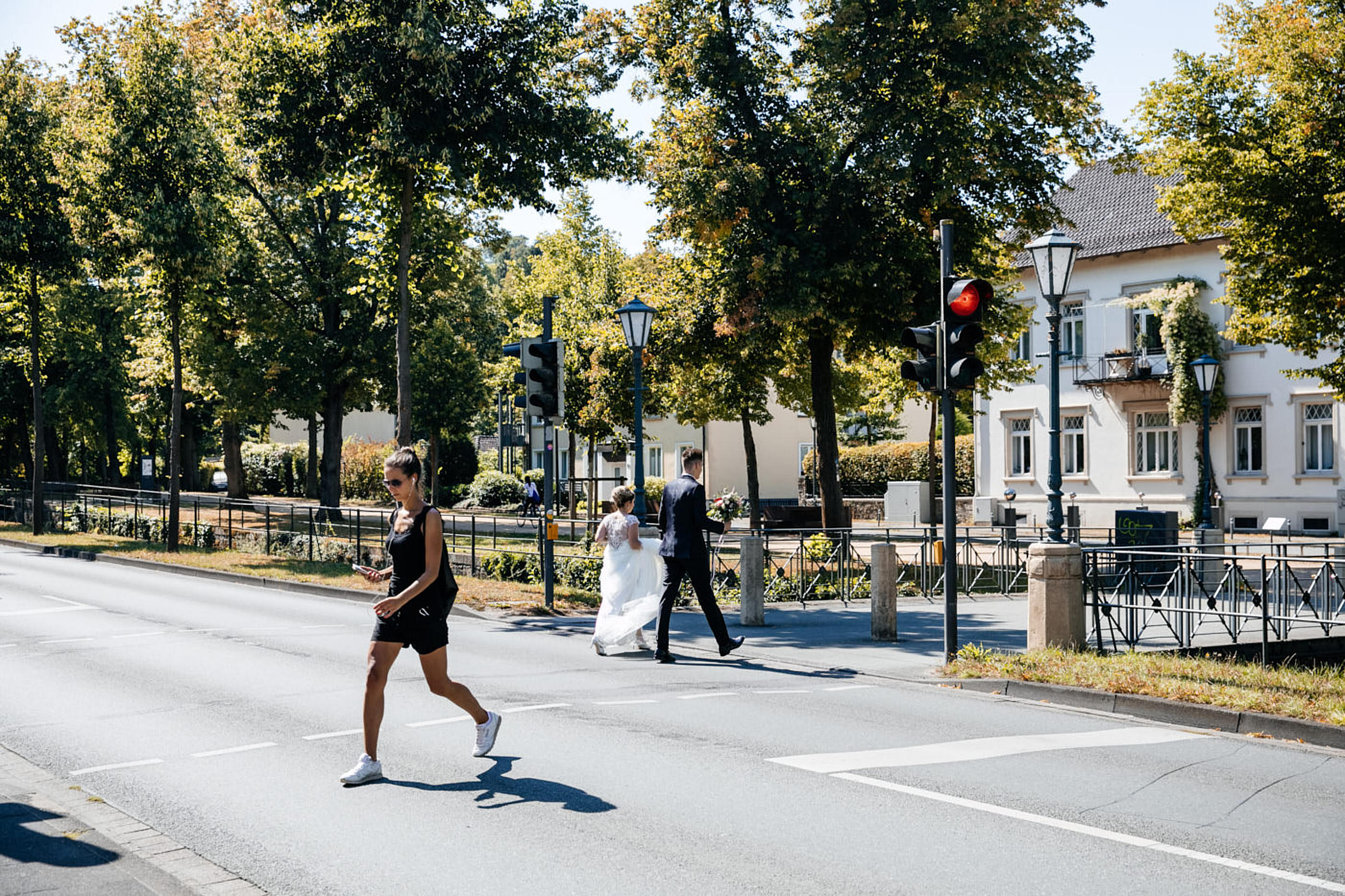 Fotoshooting am Hochzeitstag. Hochzeitspaar geht &uuml;ber die Ampel. Begleitung als Hochzeitsfotograf in Detmold.