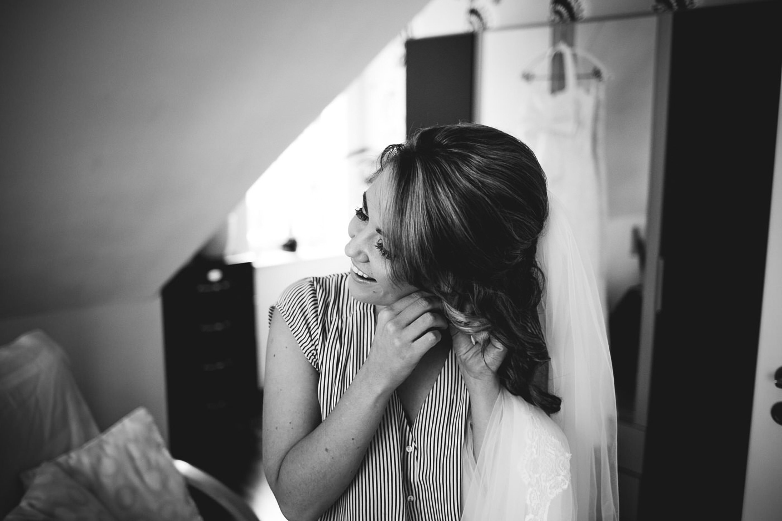 Braut bringt die Ohrringe an.