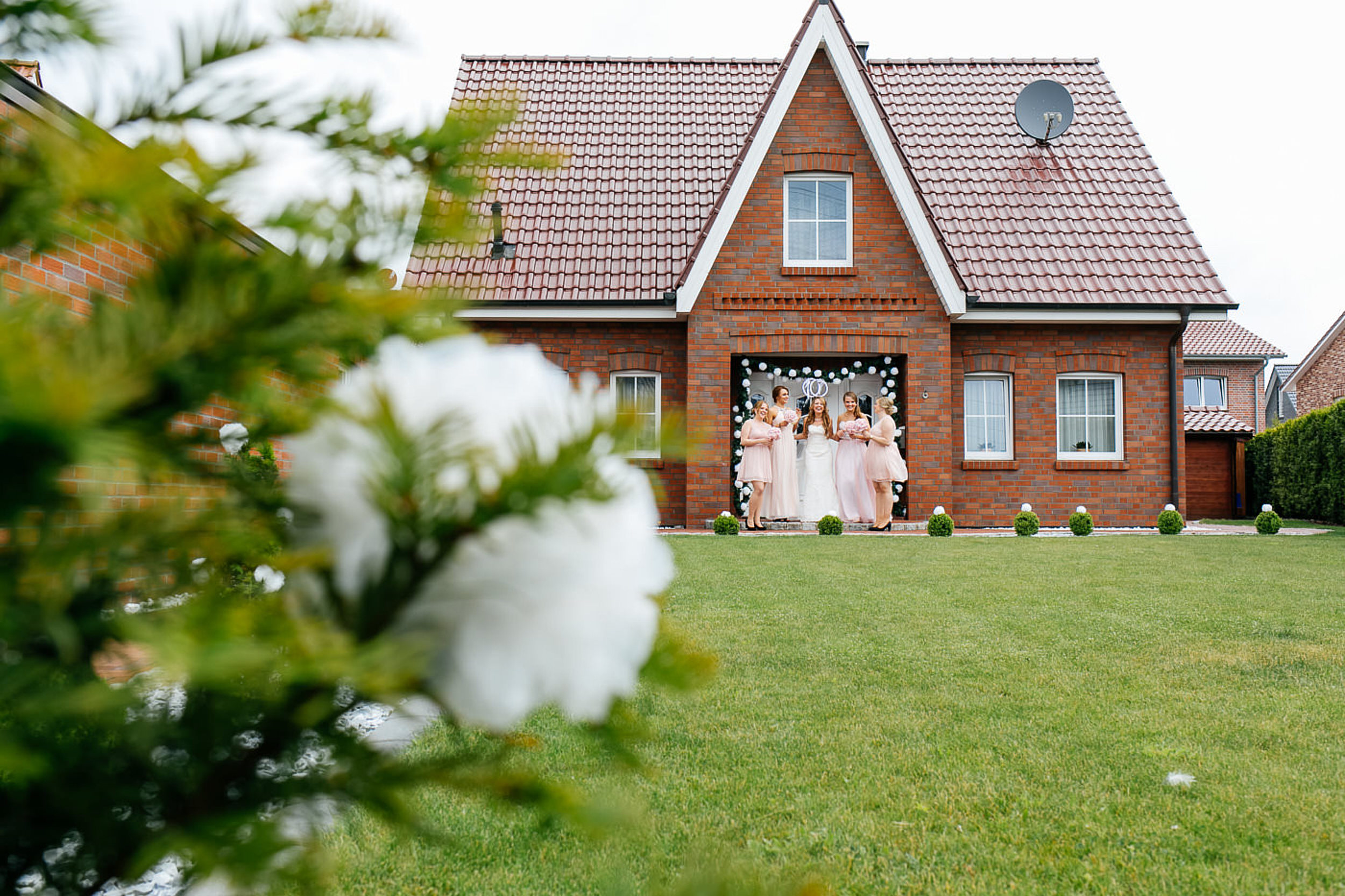 Brot mit den Jungfern stehen vorm Haus und machen Selfies. Blume im Vordergrund