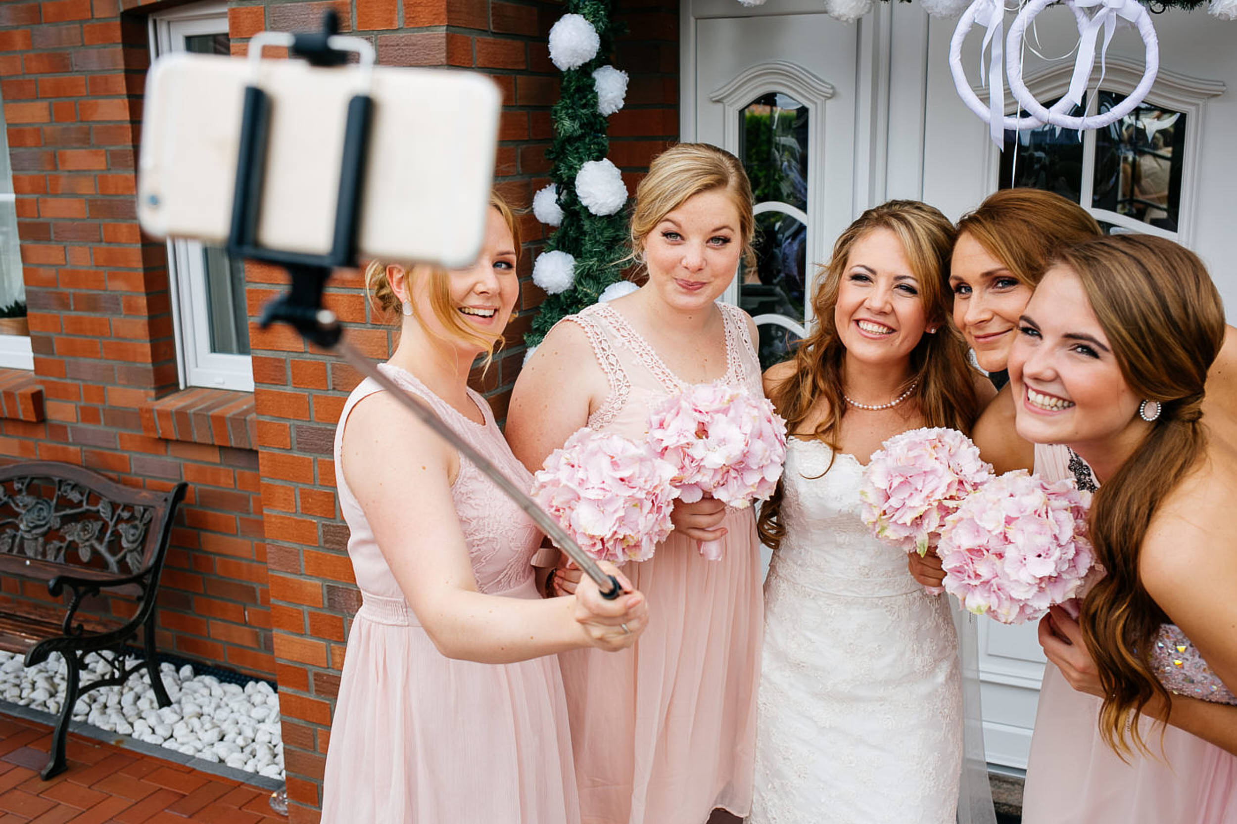 Braut mit den Jungfern machen ein Selfie Bild. Handy auf dem Selfie Stick.