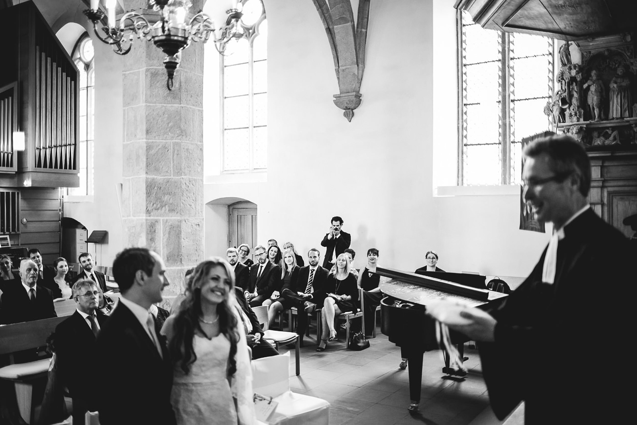 Kirchliche Trauung Brautpaar steht vom Altar und schaut zum Fahrer. Braut l&auml;chelt.