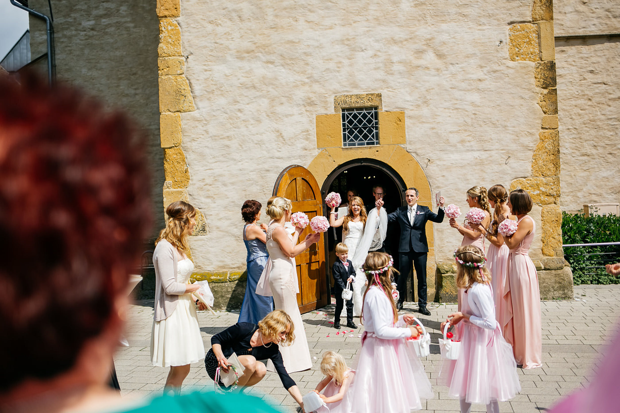 Kirchliche Trauung. Brautpaar kommt jubelnd aus der Kirche raus.