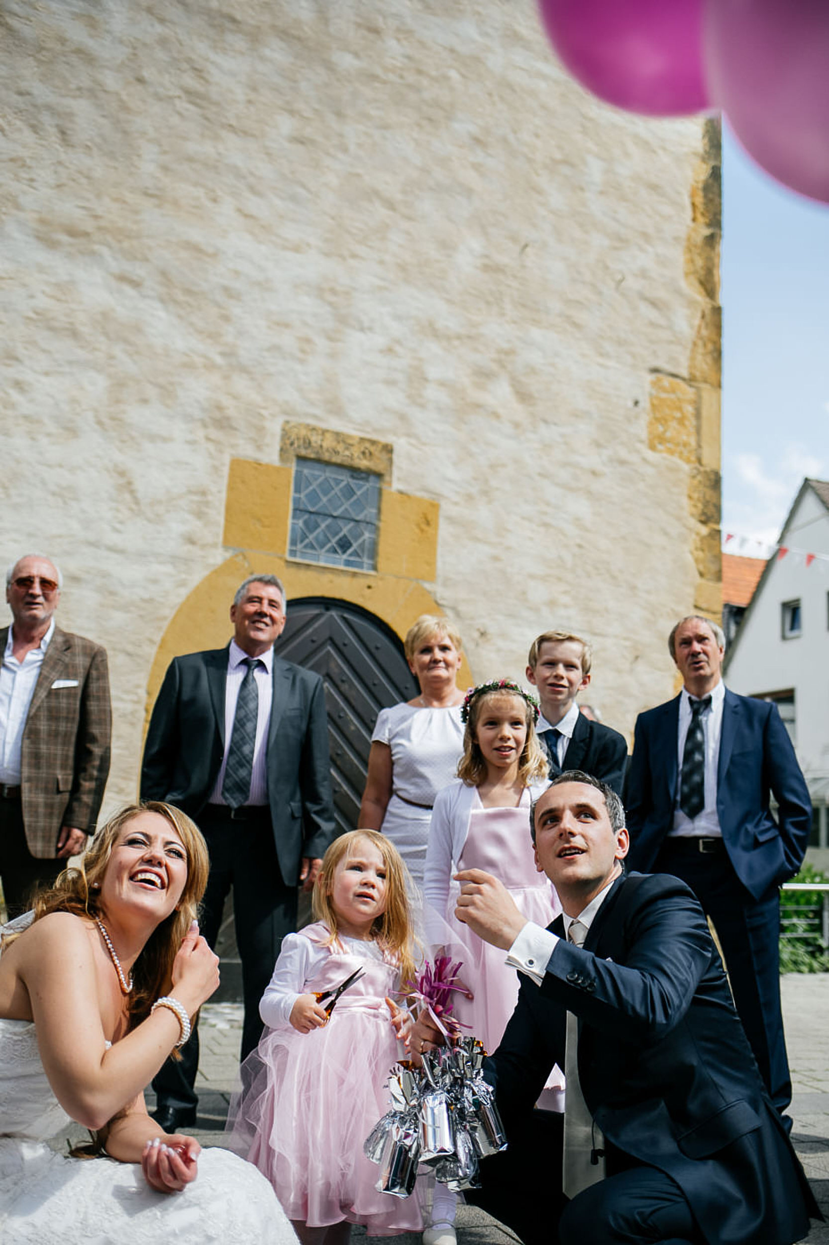 Kirchliche Trauung. Das Brautpaar l&auml;sst die pinke Luftballons los.