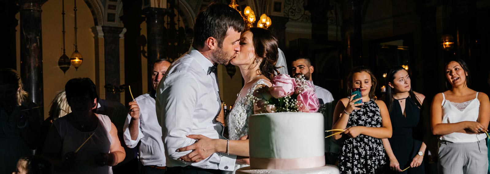 Brautpaar k&uuml;sst sich. Hochzeitstorte.