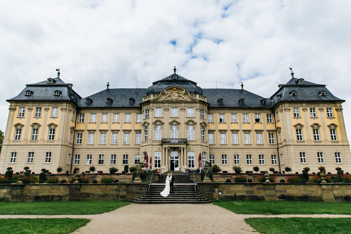 Das Brautpaar beim Fotoshooting. Braut und Bräutigam stehen vor dem Schloß. Hochzeitsfotograf in Schweinfurt.