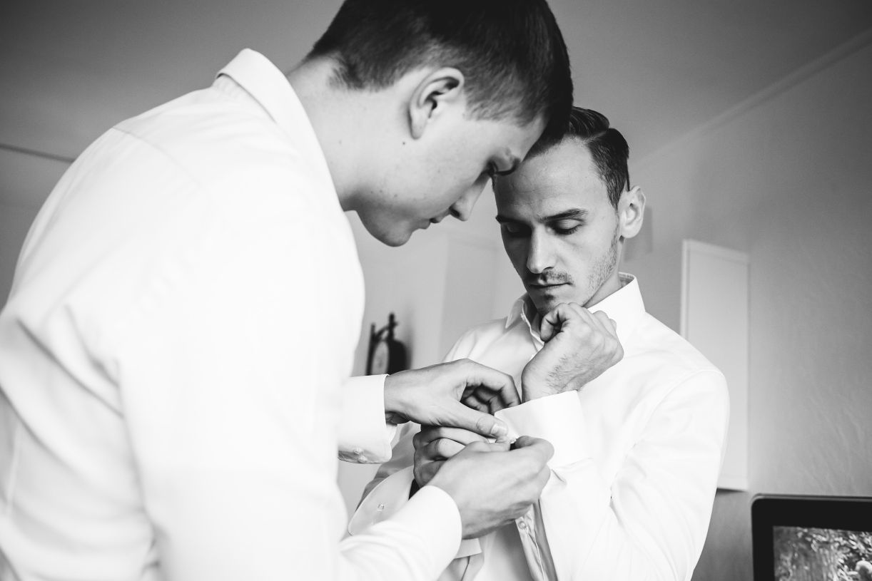 Vorbereitung des Bräutigams am Hochzeitstag. Trauzeuge hilft dem Bräutigam die Manschettenknöpfe anzubringen. Hochzeitsfotograf in Schweinfurt